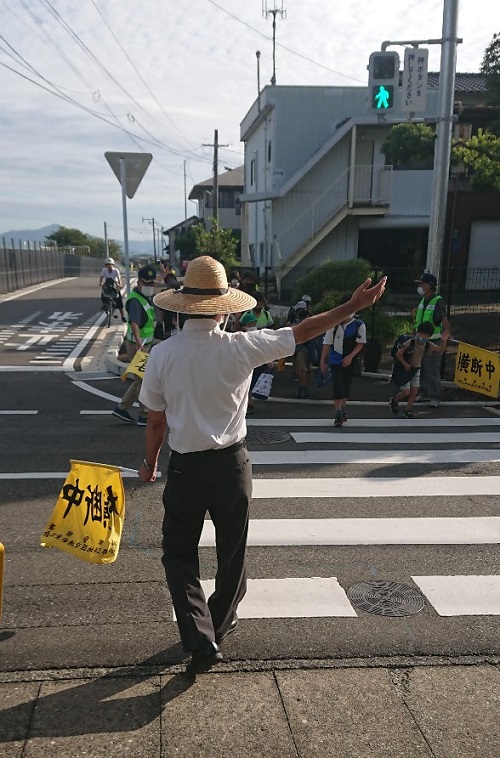 横断歩道を渡る生徒をサポートする井上校長先生