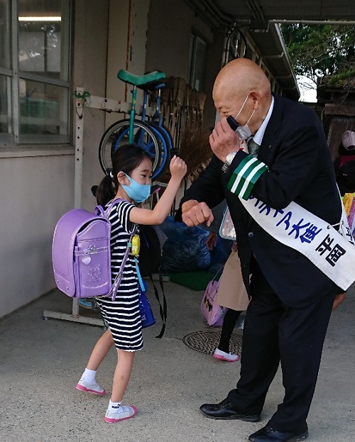 生徒とあいさつのあとｍ肘タッチをする平岡さん